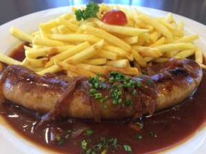 Schweinsbratwurst an Zwiebelsauce mit Pommes frites